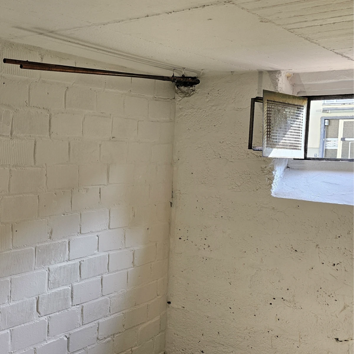 Kellerwand nachher Sanierter Keller mit frisch gestrichenen weißen Wänden und geöffnetem Fenster nach Brandschaden-Reparaturarbeiten.