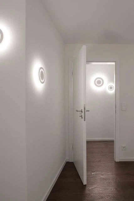 Renovierungsarbeiten innen Maler Scholz 6 Weißer, frisch renovierter Flur mit minimalistischen runden LED-Wandleuchten und offener Tür.